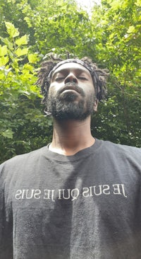 a man with dreadlocks wearing a black t - shirt